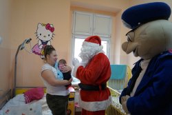 Święty Mikołaj, sierż. Pyrek pozują do wspólnego zdjęcia z małym pacjentem szpitala.