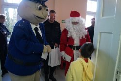 Święty Mikołaj, sierż. Pyrek oraz starszy brygadier Damian Jankowiak wręczają prezent małemu pacjentowi.